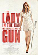 La dame dans l'auto avec des lunettes et un fusil